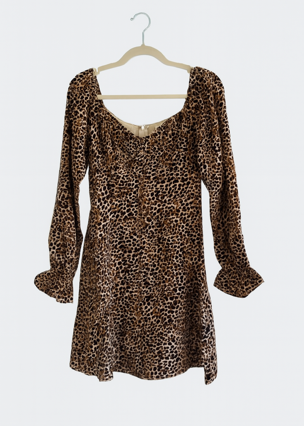 Leopard print dress on a hanger against a white background