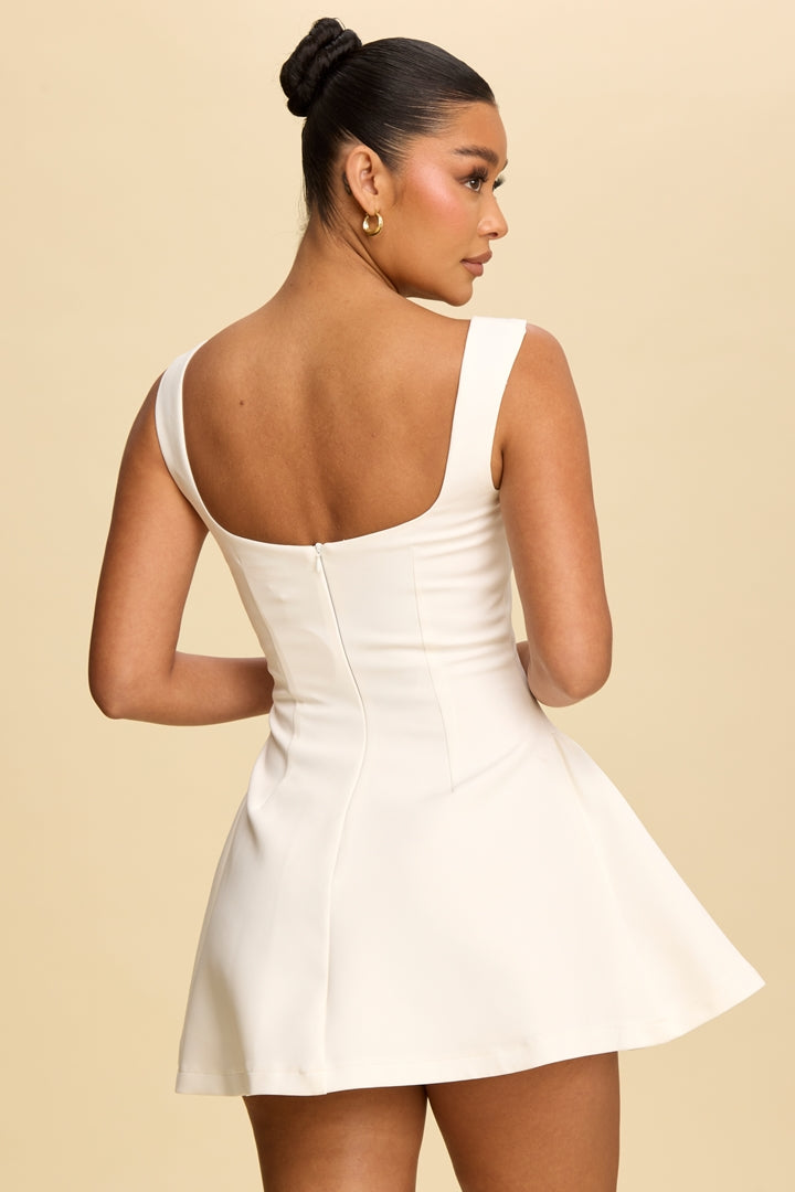 Woman wearing a white dress against a beige background