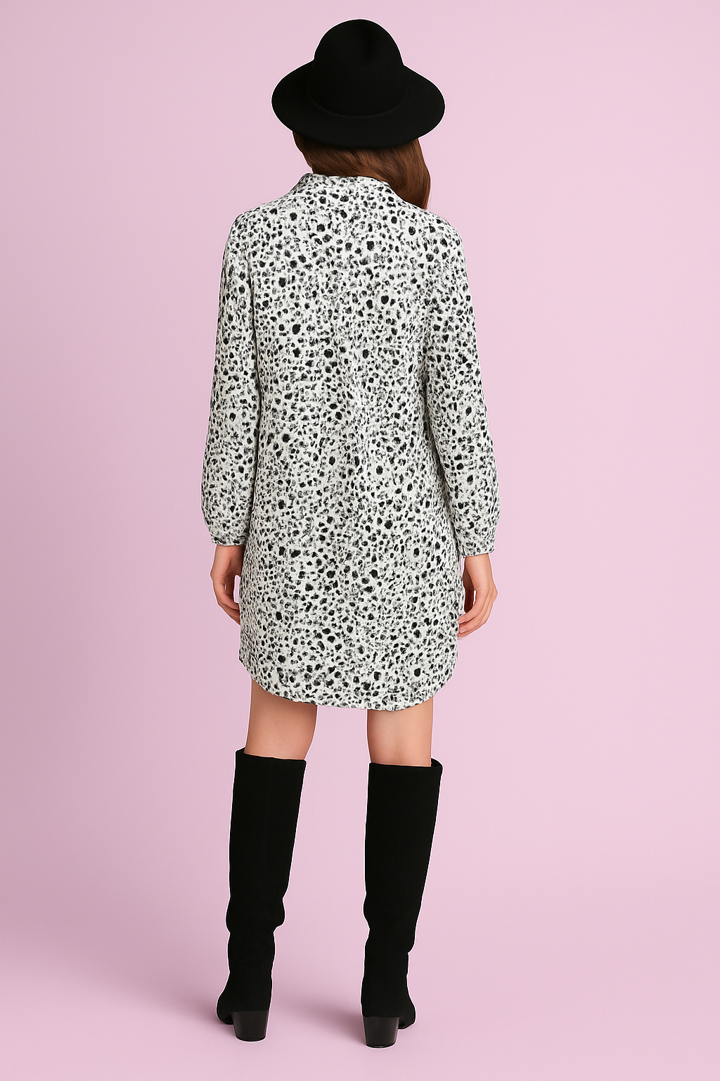 Woman wearing a patterned dress and black boots on a pink background