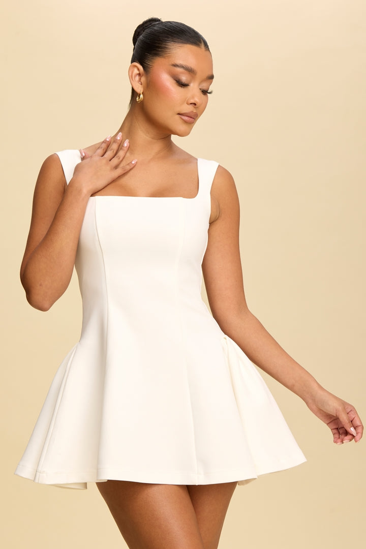 Woman wearing a white dress against a beige background